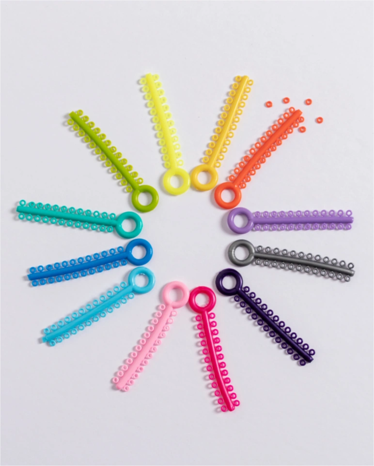 Colorful orthodontic elastic ligature ties arranged in a circle on a white background.