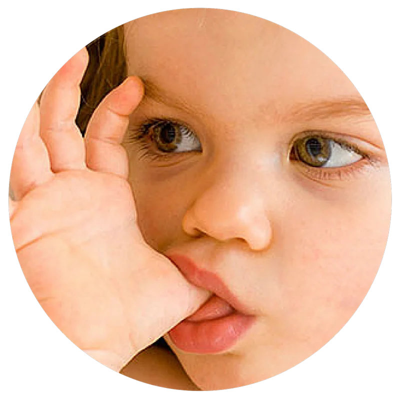 A close-up of a young child sucking their thumb and looking to the side.